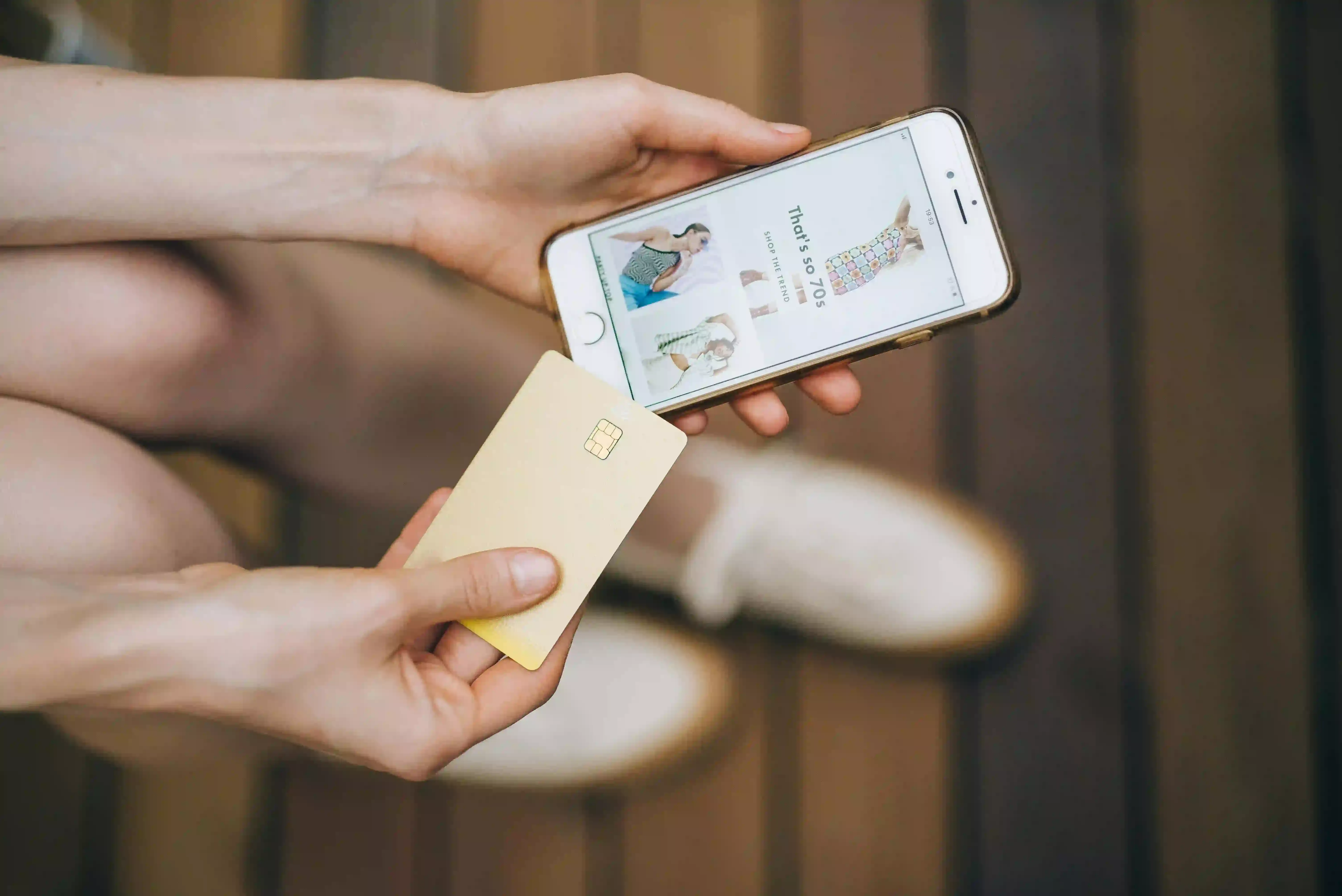 Osoba trzymająca iPhone'a i kartę płatniczą